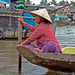 Market-woman steering her boat on the Hậu Giang river