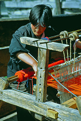 A young woman weaving with a simple loom