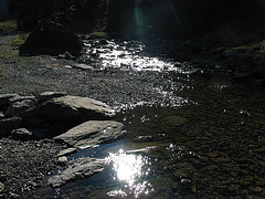 Glitzerndes Sonnenlicht im Bergbach