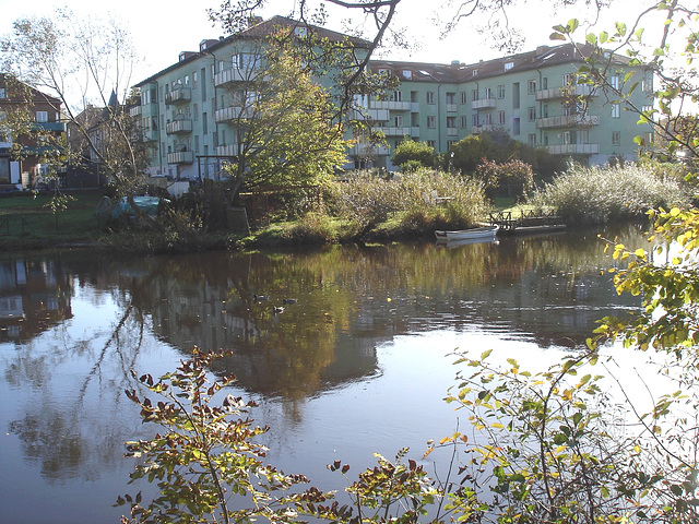 Apartments building and rowboat by the river /  Édifice à appartements avec chaloupe et canards