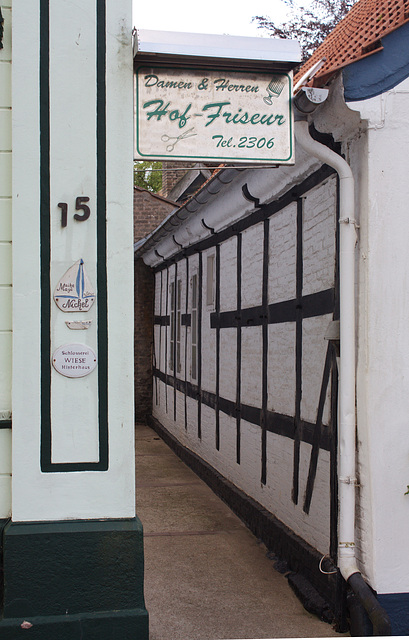 Entrance to a locksmith's shop and a hairdresser in the house at the back