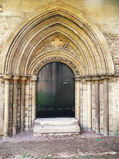 peterborough cathedral ;the doorway to peterborough's refectory to the south of the cloister is very ornate, with dragons in the stiffleaf of its tympanum. it dates from the early mid c13.