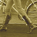Cycliste en bottes à talons hauts / Walking Swedish biker in jeans & high-heeled boots at her cell phone - Sepia