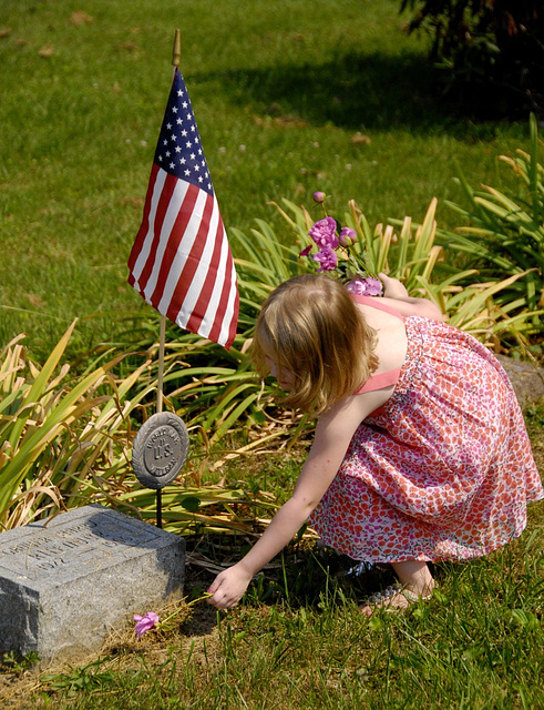 Little Emma, her father active military, places flowers