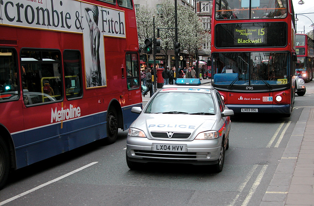 Police car squeezing between two busses on Oxford Street