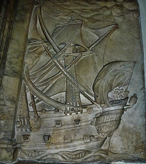 barking church, essex,stern of "the lennox", a detail of the splendid memorial to captain john bennett, 1706. figures can be seen on board: one holds his sword aloft, two blow trumpets.  his chest tomb outside also depicts his ship.
