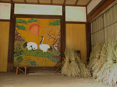 A couple of cranes and bundles of rice stalks