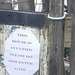 A sign pinned on the gate of the old house.