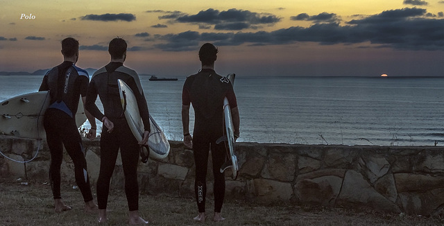 Surfers a la puesta de sol