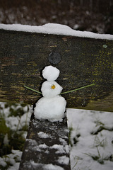 Little snowman sitting on bench