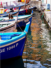 I gozzi genovesi ancorati al molo del porto con i riflessi di Camogli nel mare