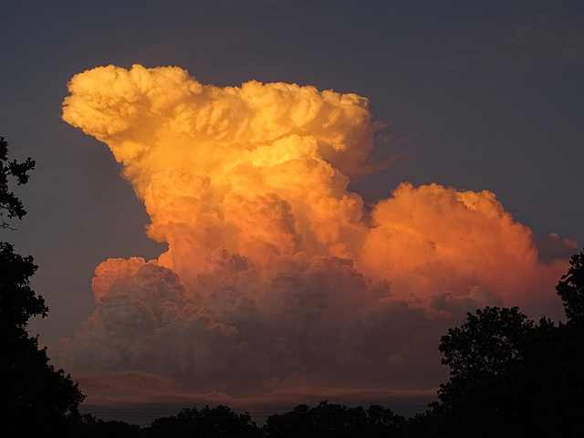 Cumulonimbus clouds in the east reflecting the sunset in the west