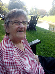Grandma im Park auf Sonnenstuhl am Wasser