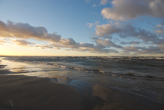 Der nasse Sand und die Wellen beim Sonnenuntergang
