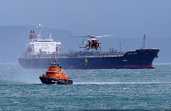 RNLI lifeboat 17-32 (MMSI: 235005118) receiving a crewman from AgustaWestland AW189 (G-MCGS) with Singaporean-registered oil/chemical tanker MTM St Jean (MMSI: 564475000) nearby