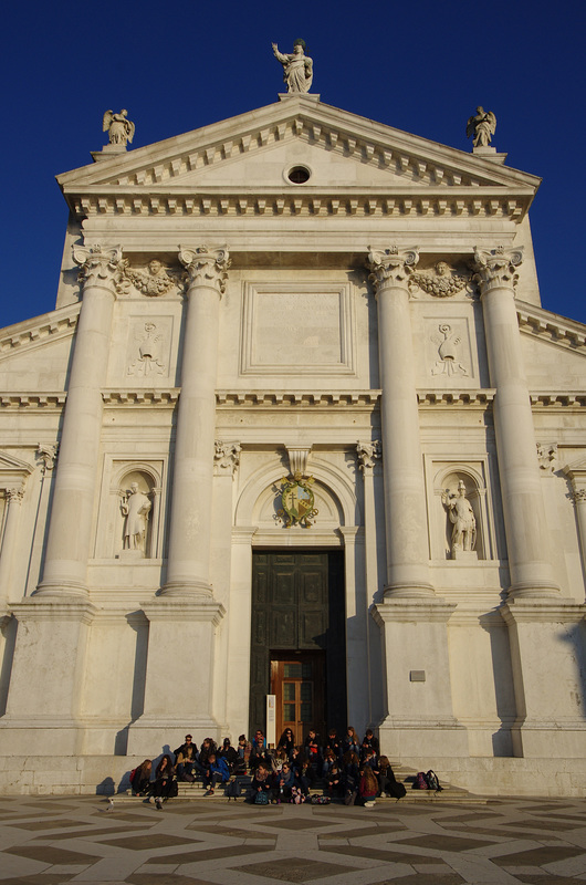 Students enjoying the sun in front of the Palladian facade of Chiesa di San Giorgio Maggiore