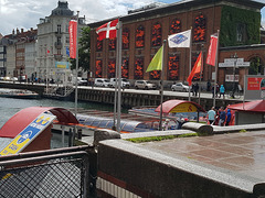 Flaggenparade im alten Hafen von Kopenhagen. Im Hintergrund Schwimmwesten von Ertrunkenen im Kunstmuseum zum Thema Einwanderung
