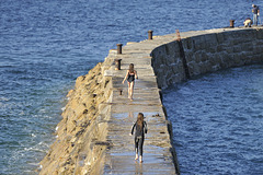 Girls running out to dive off the end of the sea wall. Sennen cove ~ Cornwall