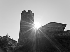 The sun sets between the tower and the houses