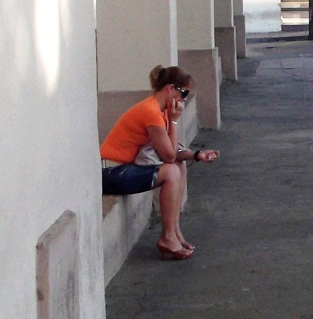 Cuban girl in high heels buzy with her cell phone