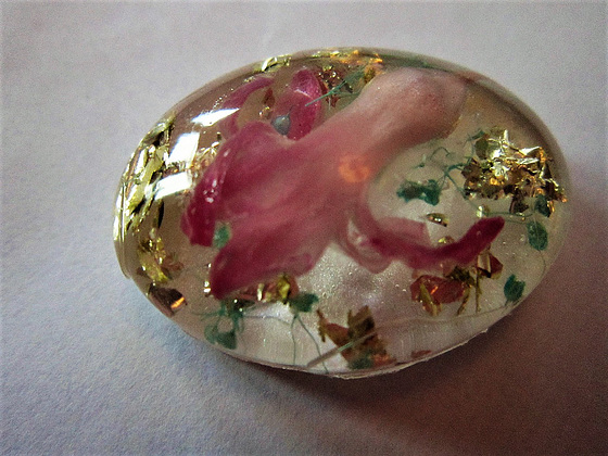 An oval with a hyacinth flower bud and gold leaf