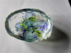 Small oval with blue flower head and greenery