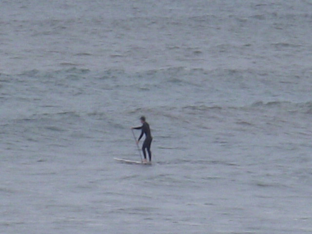 Brave man standing on his surfboard with a paddle