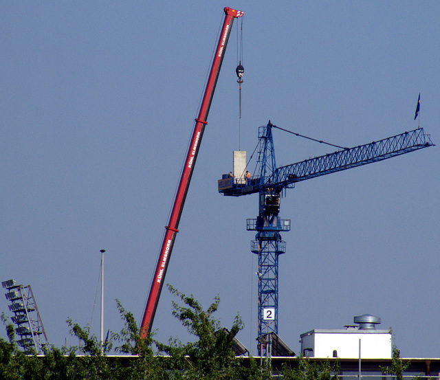 Beladen des Auslegers mit Gegengewichten und herumturnende Arbeiter