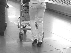Noire très sexy en talons hauts aiguilles - Black Lady in tight pale pant and high heels -  Aéroport de Bruxelles . Photofiltrée en noir et blanc.