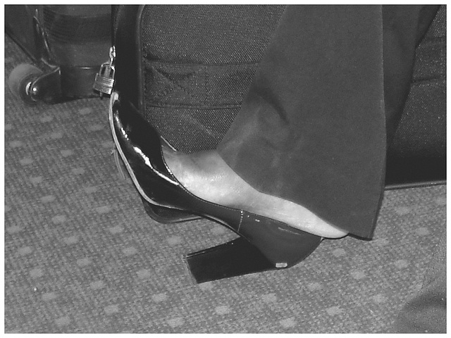 Black Lady in black & red hammer heels / Noire sexy en beaux souliers à talons hauts rouge & noir - Avec permission / With permission - Aéroport de Bruxelles / Noir et blanc avec photofiltre.