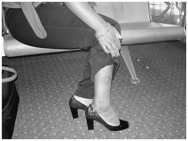 Black Lady in black & red hammer heels / Noire sexy en beaux souliers à talons hauts rouge & noir - Avec permission / With permission - Aéroport de Bruxelles / Noir et blanc avec photofiltre.