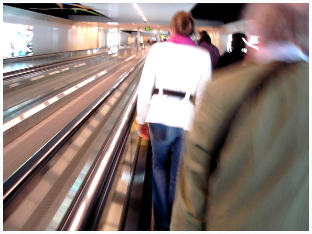 Blurry redhead in white outfit   /   Élégante Dame en blanc sur tapis mécanique -  Brussels airport.