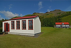 A simple schoolhouse and a rich farmhous at the background