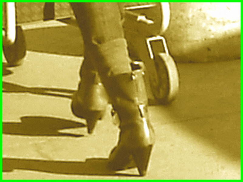 Divinité blonde en jeans et bottes à talons hauts avec boucles - Gorgeous blond Divinity in jeans and high heeled buckled boots- PET Montreal airport.  - Photofiltrée Sepia.