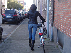 Cycliste en bottes à talons hauts / Walking Swedish biker in jeans & high-heeled boots at her cell phone