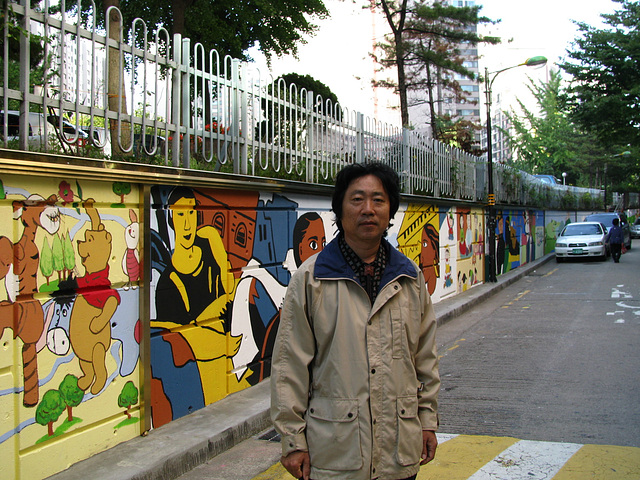 Song stands in front of painted wall=Song Ho staras antaux la pentromuro, 허성-광장동 문화의거리 뮤럴-2009okt.