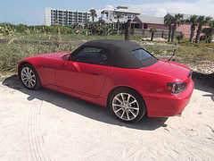 Honda rouge décapotable sur sable / Red convertible Honda on sand.