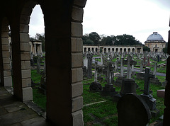 brompton cemetery, earls court,  london,designed in 1838 by benjamin baud, the arcades flanking the central path lead to a circus of similar arcades, with a circular chapel as the point de vue. there are catacombs below some of the arcades.