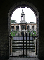 brompton cemetery, earls court,  london,designed in 1838 by benjamin baud, the arcades flanking the central path lead to a circus of similar arcades, with a circular chapel as the point de vue. there are catacombs below some of the arcades.