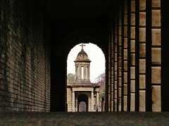 brompton cemetery, earls court,  london,designed in 1838 by benjamin baud, the arcades flanking the central path lead to a circus of similar arcades, with a circular chapel as the point de vue. there are catacombs below some of the arcades.