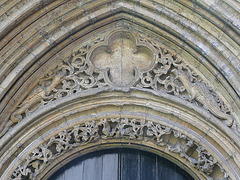 peterborough cathedral , the doorway to peterborough's refectory to the south of the cloister is very ornate, with gragons in the stiffleaf of its tympanum. it dates from the early mid c13.