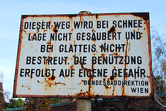 Old rusty sign warning that the road will not be treated when it is snowing