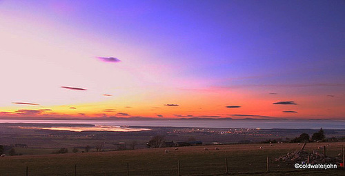 Summer skies and sunset over Findhorn Bay and the Moray Firth, with the lights of Kinloss, from Califer Viewpoint