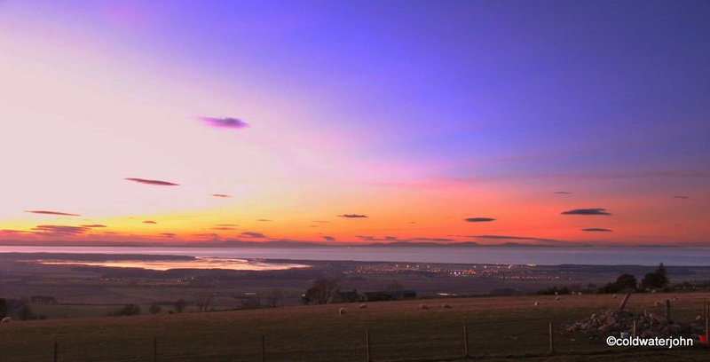 Summer skies and sunset over Findhorn Bay and the Moray Firth, with the lights of Kinloss, from Califer Viewpoint