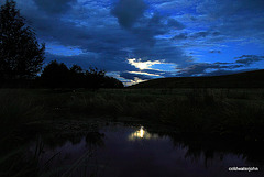 Full moon in clouds reflected in the pond