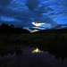 Full moon in clouds reflected in the pond