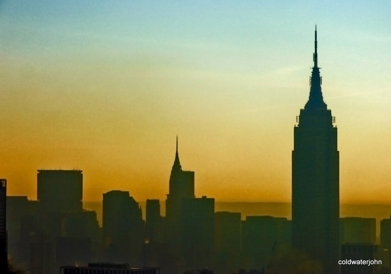 Manhattan skyline at dawn from above the Hudson river.