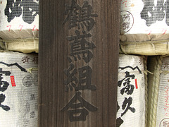 Wood board with a donor's name on it and sake barrels