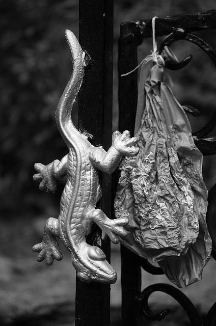 Metal sculpture of a lizard, with a burst balloon