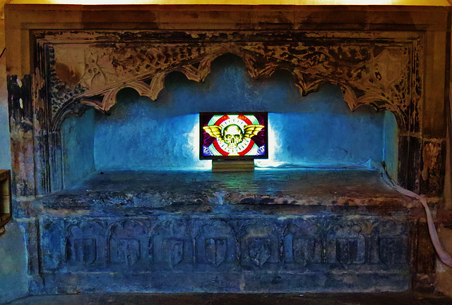 st. john the baptist's church, bristol,detail of early c16 tomb in crypt with incised slab showing merchant and wives, with part of exhibition of enamel painted glass